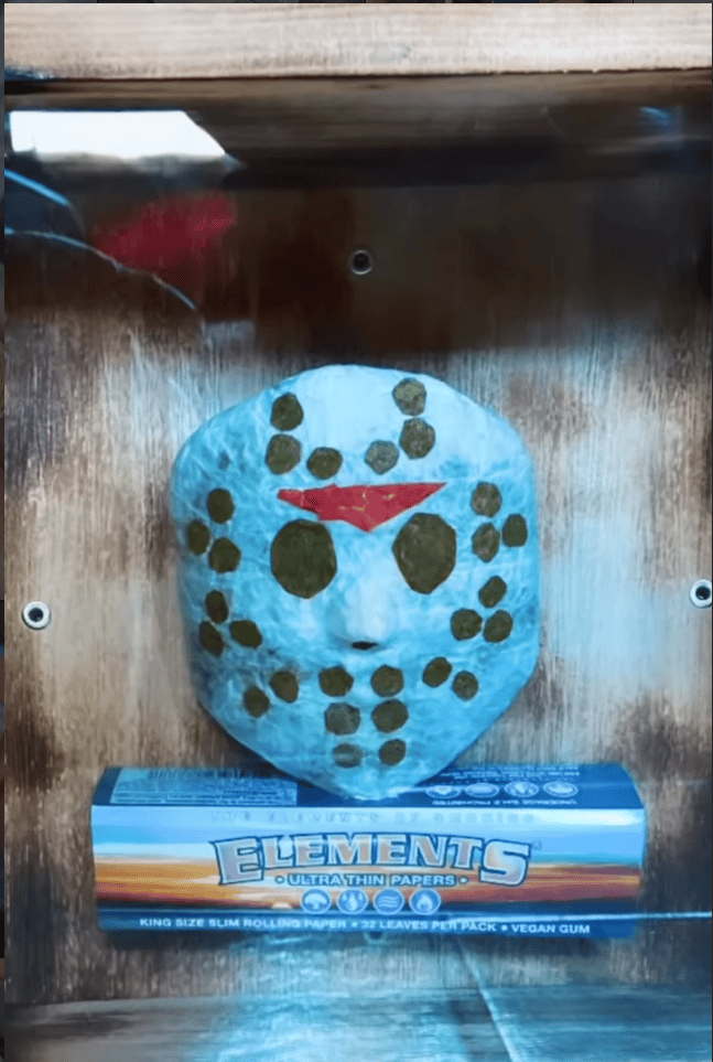 A custom light blue hockey mask displayed on top of a pack of Elements rolling papers