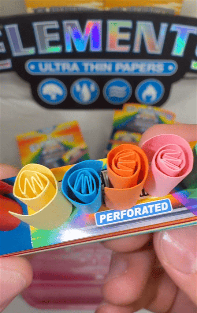 An Elements Papers Instagram post showing a hand holding a colorful pack of perforated filter tips, with four rolled tips in yellow, blue, orange, and pink