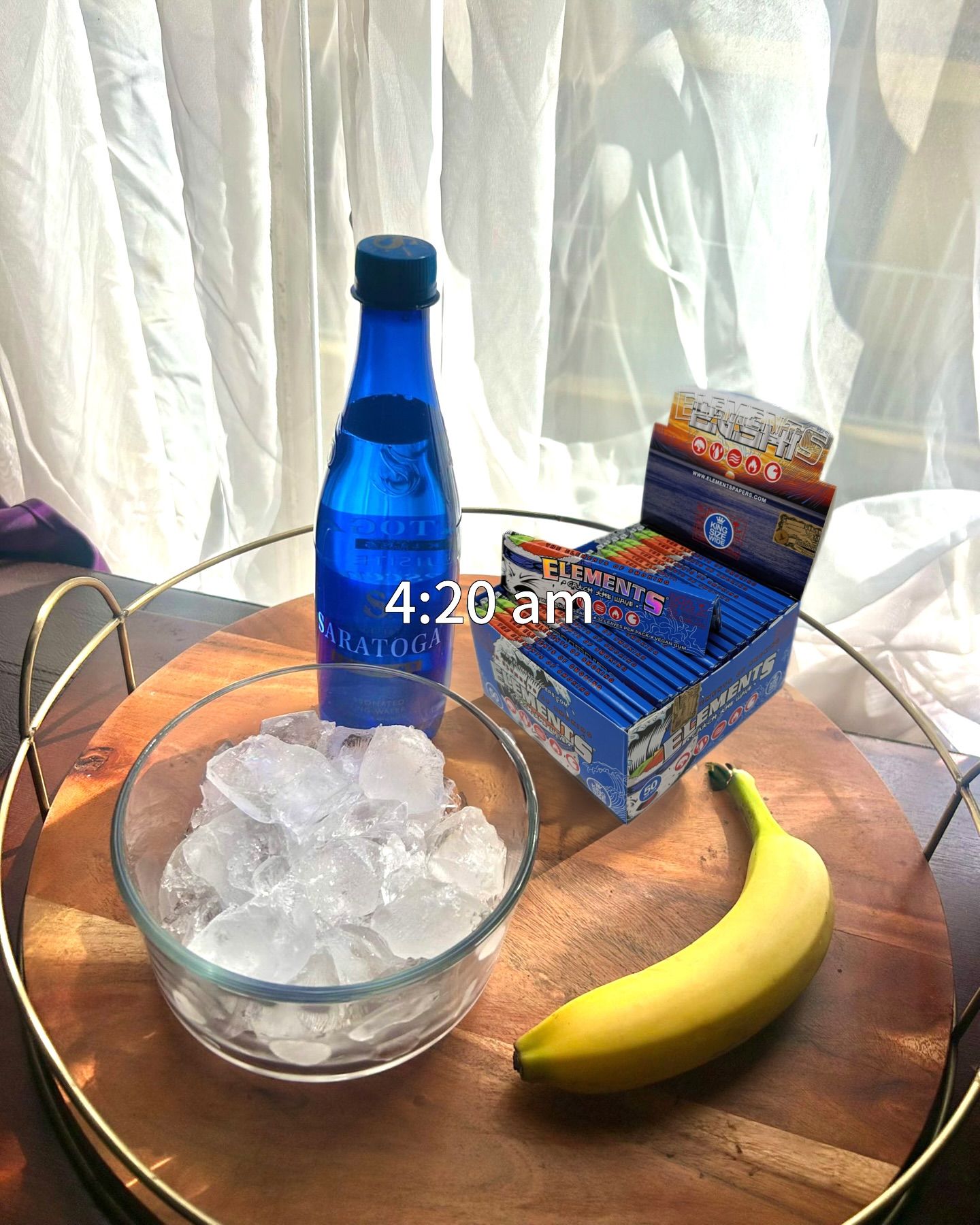 A tray with a bowl of ice, a blue water bottle, rolling papers, and a banana with "4:20 am" text overlay.